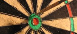 dartboard with a couple of darts stuck in it, but not in the bullseye