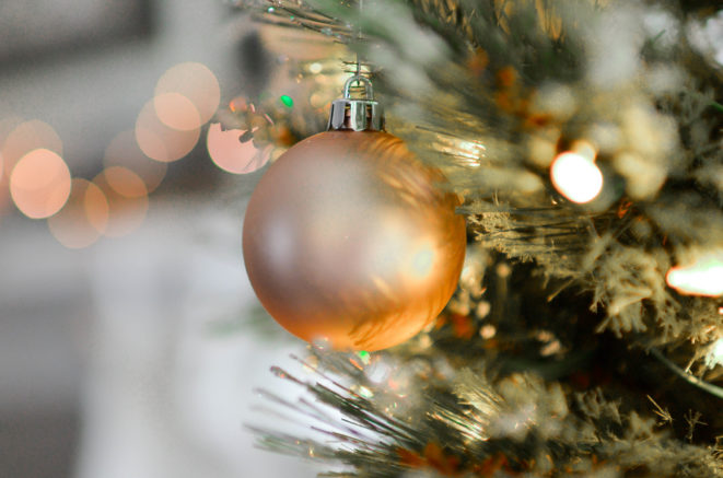 an amber-colored ornament ball hanging from a Christmas tree