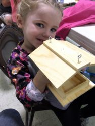 my daughter holding up a wooden bird feeder
