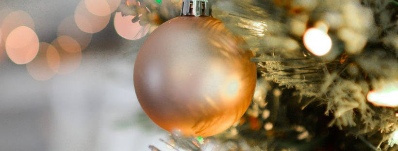 an amber-colored ornament ball hanging from a Christmas tree